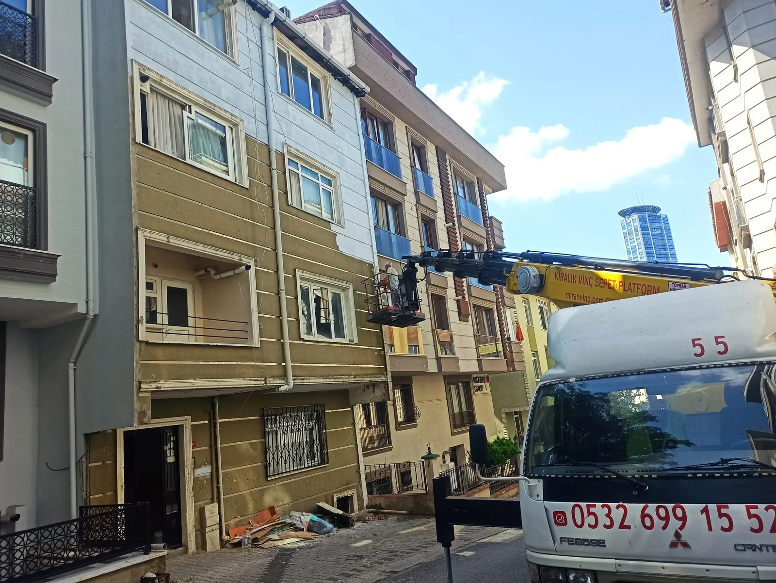 Dış cephe mantolama ve dış cephe çalışması için bina önünde konumlanmış Miran Vinç sepetli platformu