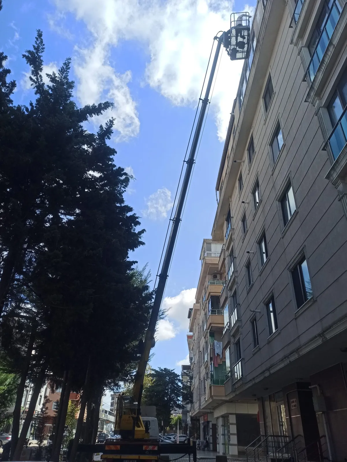 Dış cephe mantolama ve dış cephe çalışması için bina önünde konumlanmış Miran Vinç sepetli platformu