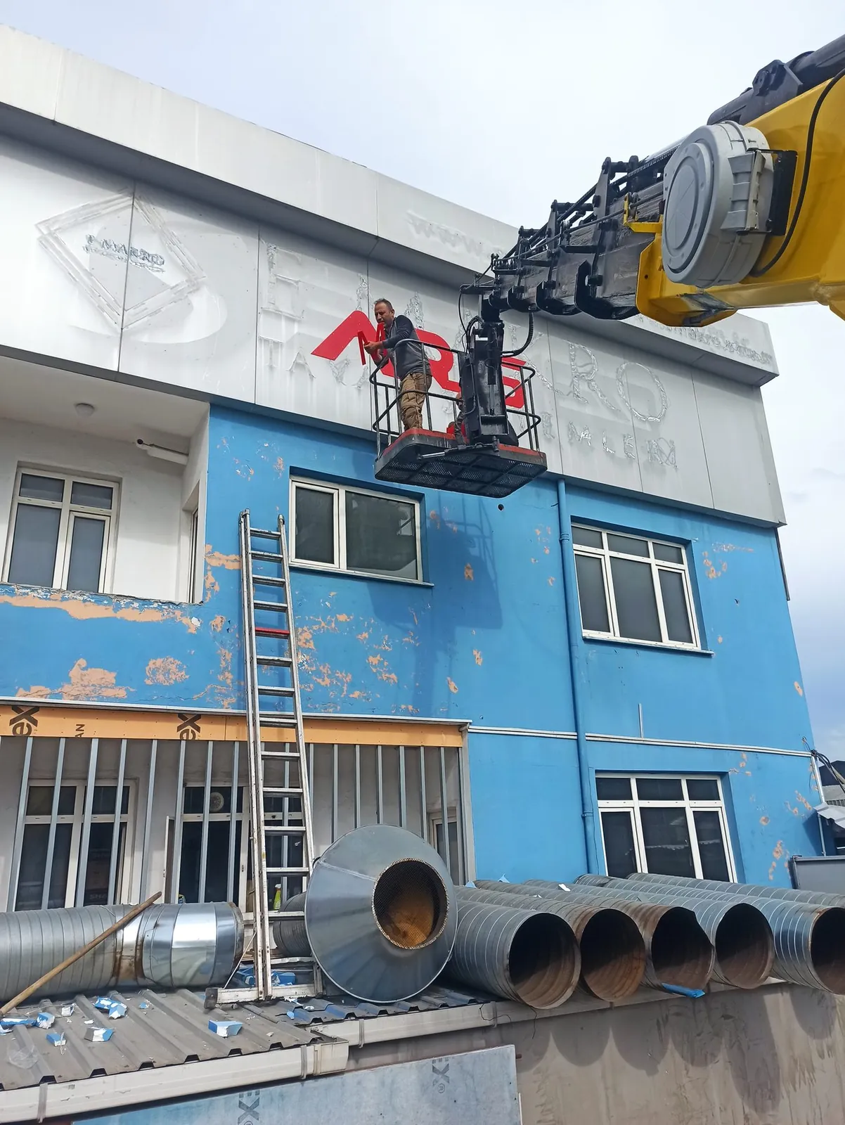 Dış cephe mantolama ve dış cephe çalışması için bina önünde konumlanmış Miran Vinç sepetli platformu