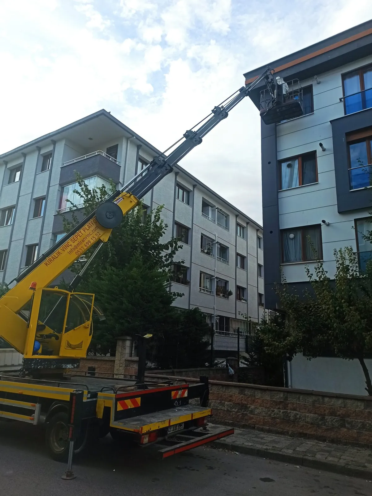 Dış cephe mantolama ve dış cephe çalışması için bina önünde konumlanmış Miran Vinç sepetli platformu